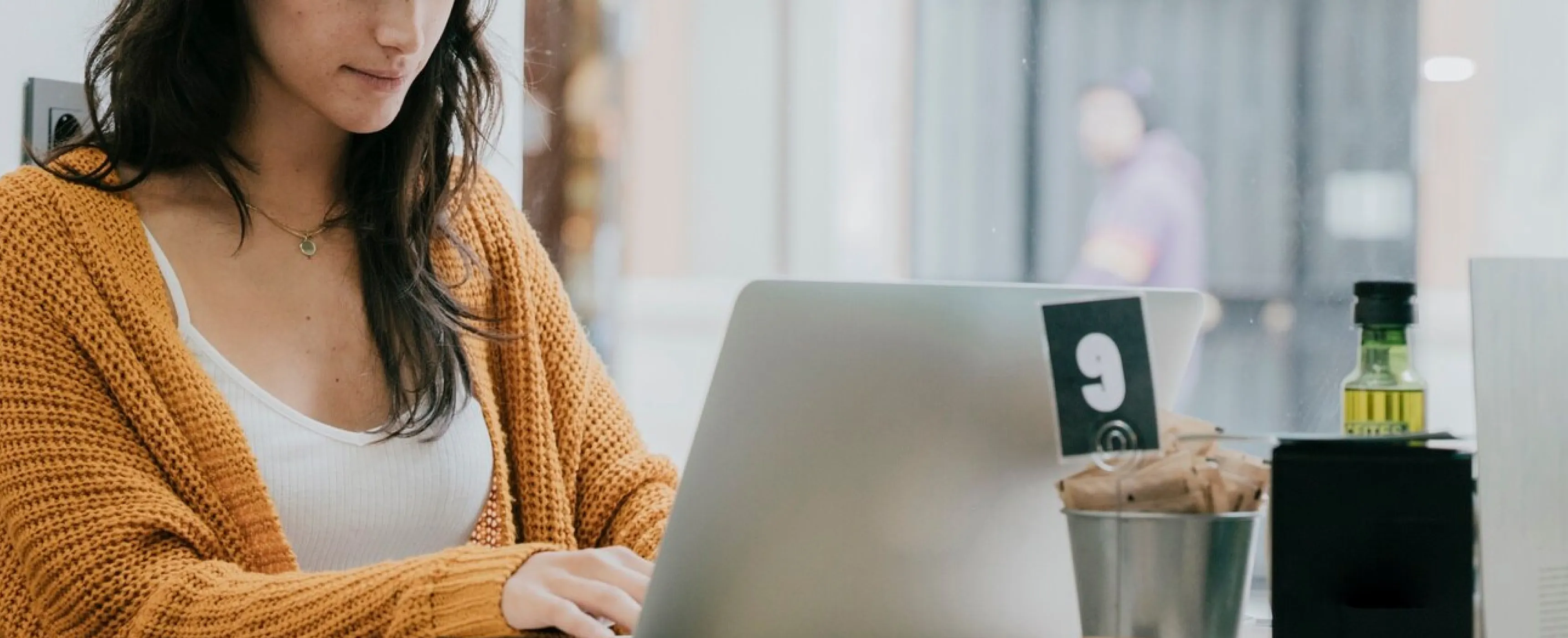 A woman at a table using a laptop, concentrating on her work.