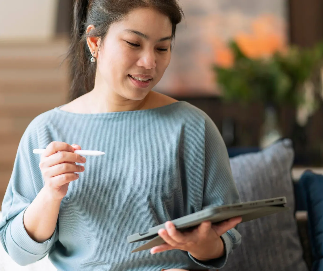 A woman on a couch, holding a tablet, representing a serene moment of interaction with technology in a cozy setting.