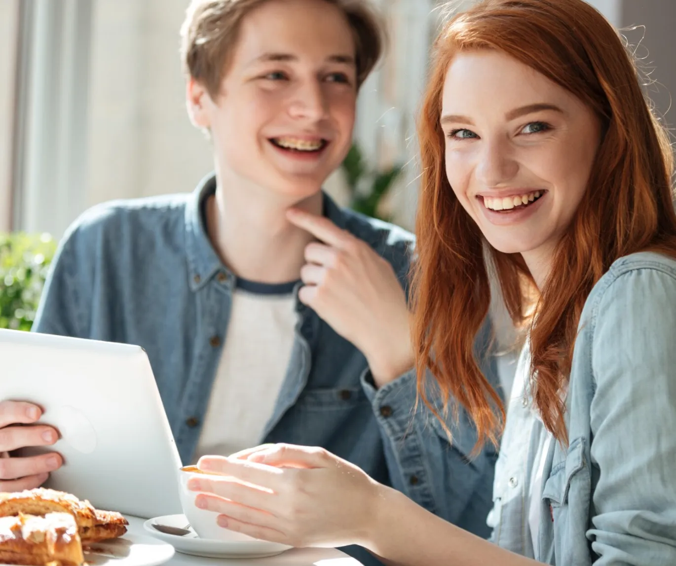 A young man and woman are at a table, appearing relaxed and engaged in a friendly discussion.