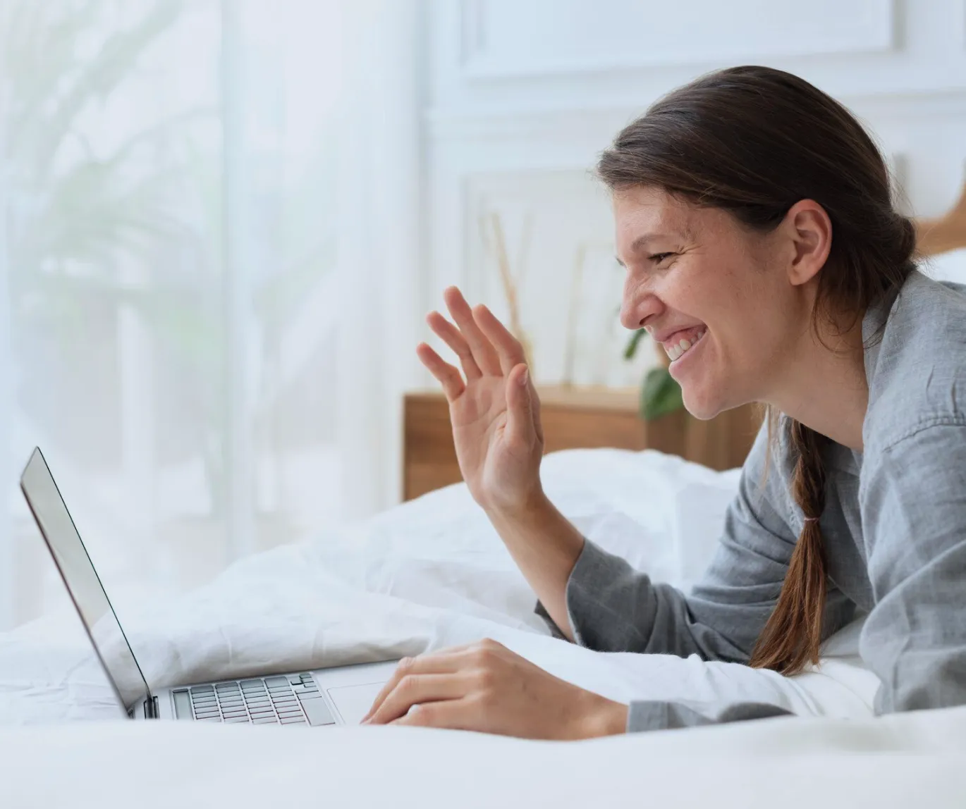 A woman is seen laughing heartily as she uses her laptop, capturing a moment of joy and engagement with digital content.