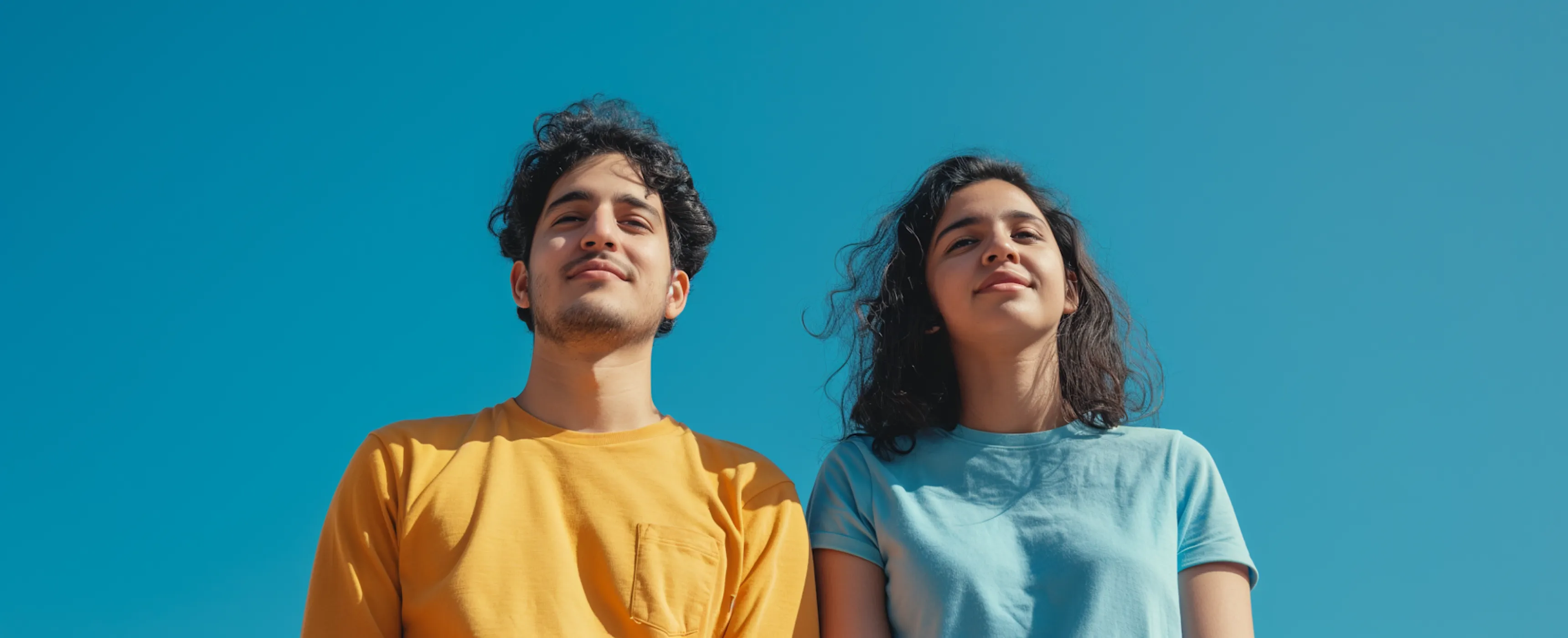 Two figures stand beneath a vast blue sky, embodying a moment of togetherness and tranquility in nature.