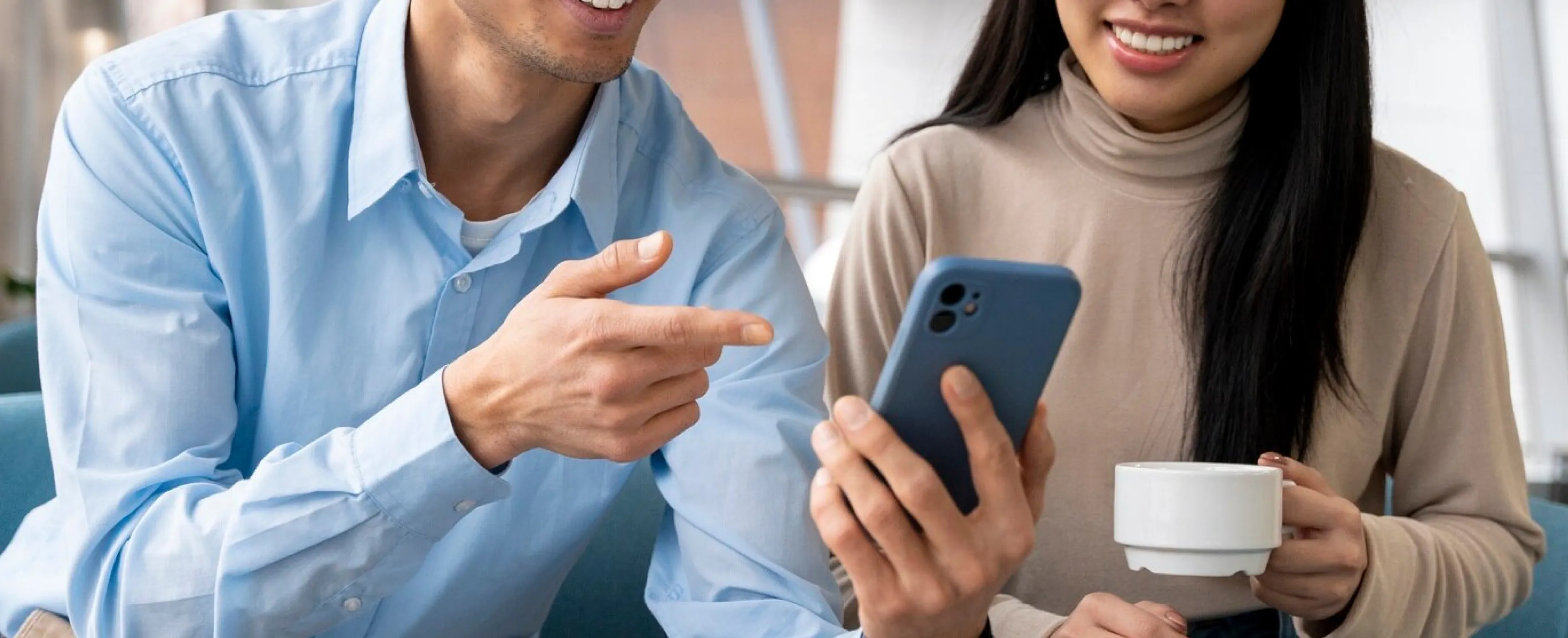 A man and woman are focused on a phone, indicating a collaborative moment of discovery or communication.